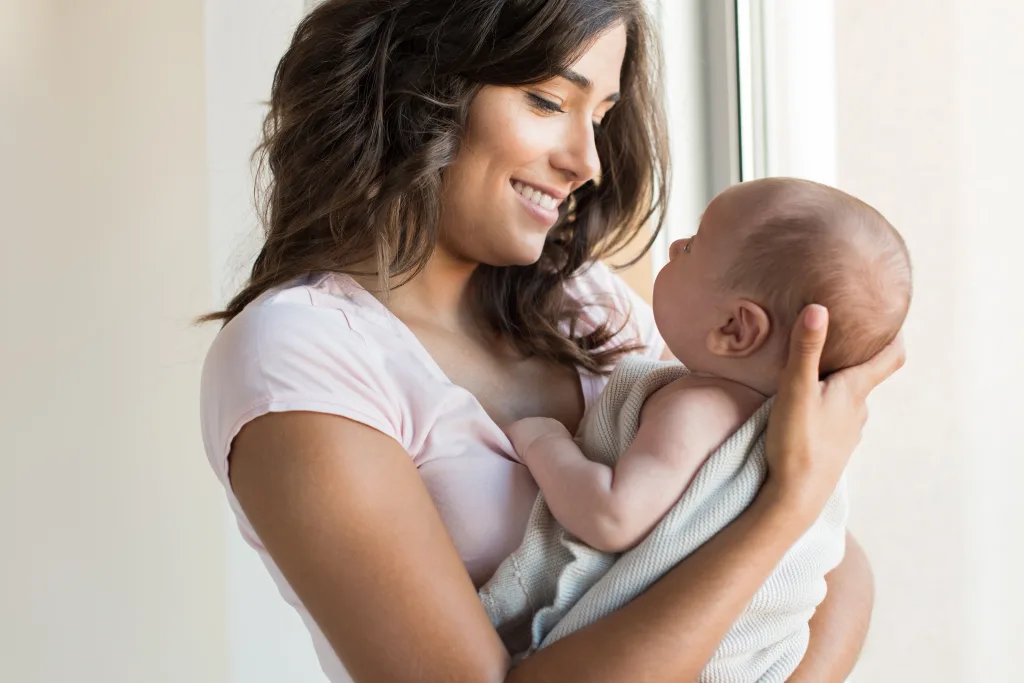 An image of pretty woman holding a newborn baby in her arms